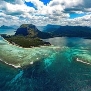 Una vista aerea di una penisola montuosa e l'illusione ottica di una cascata sottomarina nell'oceano turchese.