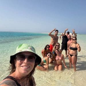 Un gruppo WeRoad scatta un selfie mentre posa nell'acqua bassa e turchese di un banco di sabbia.