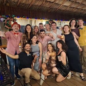 A WeRoad group trip smiling and posing together for a photo at a festive party with Christmas decorations.