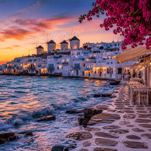 Una passerella in pietra lungo il mare conduce a un paese di case bianche e mulini a vento su una collina sotto un tramonto colorato.