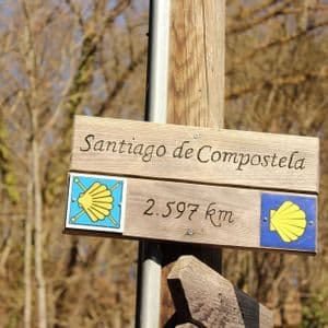 Un cartello di legno sul Cammino di Santiago che indica 2.597 km a Santiago de Compostela.