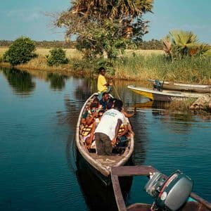 Un viaggio di gruppo WeRoad in canoa di legno lungo un fiume calmo e stretto, circondati da una vegetazione lussureggiante.