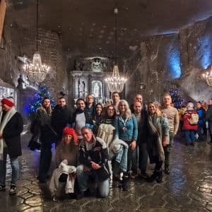 Un viaje en grupo de WeRoad posa para una foto dentro de una caverna de roca decorada con candelabros de cristal y una capilla tallada.