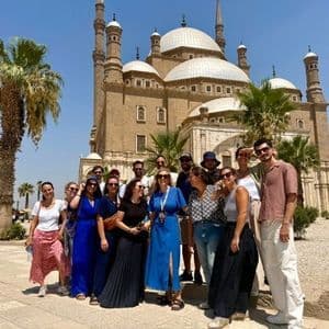 Un groupe WeRoad pose pour une photo devant une grande mosquée historique avec plusieurs dômes et minarets.