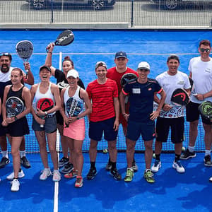 Una foto dall'alto di un gruppo WeRoad in posa su un campo da padel blu con le racchette in mano.