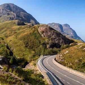 Une route panoramique sinueuse à travers un col de montagne verdoyant par temps clair.