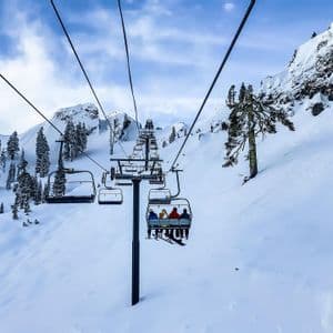 Un viaggio di gruppo WeRoad in seggiovia su un pendio montano innevato con alberi sempreverdi sotto un cielo nuvoloso.
