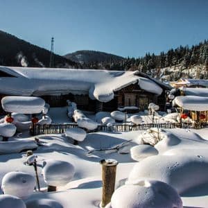 Cabañas de madera en un pueblo de montaña cubiertas por una gruesa capa de nieve en un día brillante y soleado.