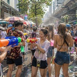 Un gruppo WeRoad in battaglia d'acqua con pistole colorate in una via affollata durante un festival.