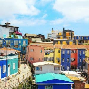 Case dai colori vivaci, addossate su una collina soleggiata sotto un cielo azzurro.
