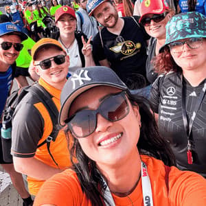 A WeRoad group trip smiles for a selfie photo in a large crowd at an outdoor event.