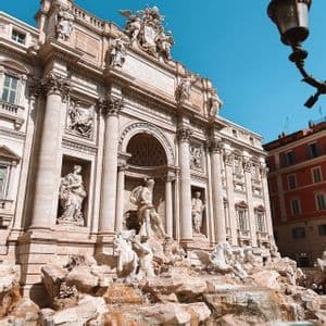A low-angle daytime view of a large, ornate fountain with intricate statues built against a classical building.