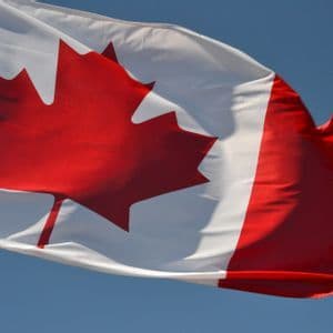 La bandiera canadese, con una prominente foglia d'acero rossa, sventola contro un cielo azzurro limpido.