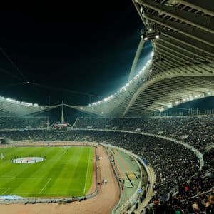 Folla che riempie uno stadio sportivo splendidamente illuminato di notte durante una partita di calcio.