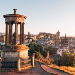 Un classico monumento in pietra domina il profilo storico di una città con torri ed edifici alla calda luce del sole.