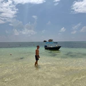 Island hopping in the archipelago Traveler standing in shallow turquoise water next to a small boat during an island hopping tour