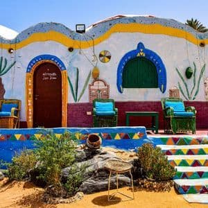 Facciata di edificio colorata e vivacemente dipinta con sedie da patio esterne e gradini in pietra geometricamente decorati.