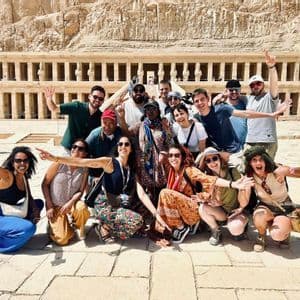 Un gruppo di viaggio WeRoad in posa e sorridente davanti a un antico tempio in pietra con colonne.