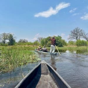 Un viaggio di gruppo WeRoad a bordo di tradizionali canoe scavate nel legno attraverso acque paludose sotto un cielo blu.