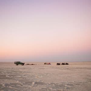 Un viaggio di gruppo WeRoad in pausa su una distesa di sale desertica con quad e un fuoristrada al tramonto