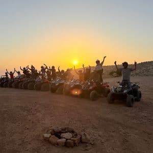Un viaggio di gruppo WeRoad di viaggiatori in posa sui quad con le braccia alzate al tramonto su un altopiano sterrato arido