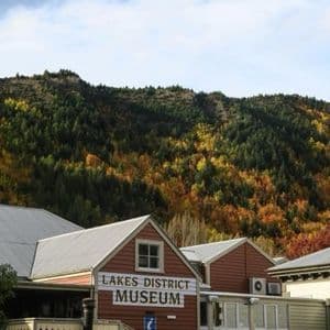 Edificio del museo del distretto dei laghi con un tetto in metallo contro una montagna boscosa con alberi autunnali colorati