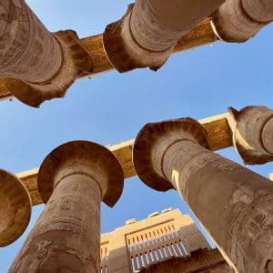 Inquadratura dal basso di antiche colonne di pietra scolpite che si ergono verso un cielo azzurro e limpido in un tempio storico all'aperto