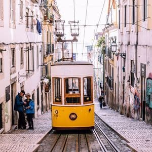 Un funiculaire jaune sur des rails, au milieu d'une rue pavée étroite et escarpée, entre des bâtiments.
