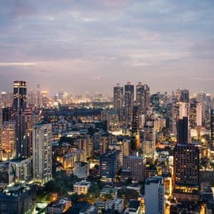 Une vaste ligne d'horizon urbaine avec des gratte-ciel illuminés sous un ciel nuageux au crépuscule.