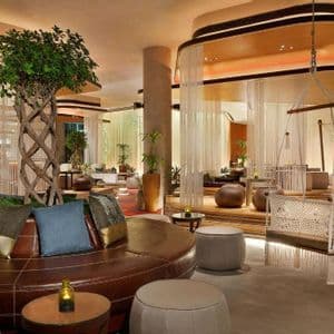 L'intérieur d'un salon moderne avec un canapé circulaire en cuir marron autour d'un arbre au tronc tressé et une balançoire suspendue.