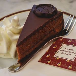 A slice of original Sachertorte with whipped cream on a plate in Vienna.
