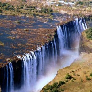 Vista aérea de una enorme cascada donde un ancho río se precipita por un largo acantilado hacia una profunda y estrecha garganta.