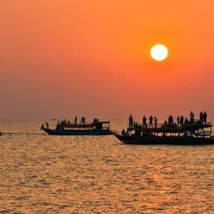 Un groupe WeRoad en silhouette sur des bateaux, admirant le coucher de soleil sur l'eau.