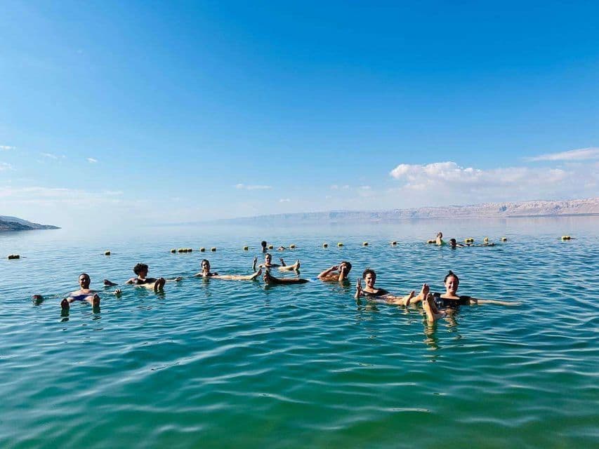 Un voyage de groupe WeRoad flottant sans effort sur le dos dans une mer calme sous un ciel bleu clair.