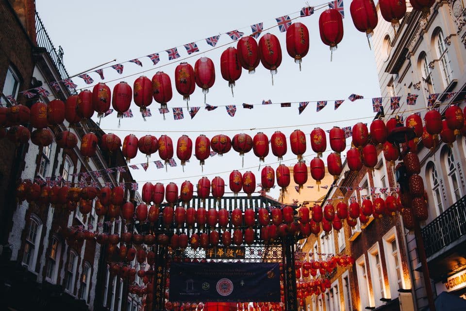Des lanternes chinoises rouges et de petits drapeaux britanniques ornent une rue urbaine bordée de bâtiments en briques.