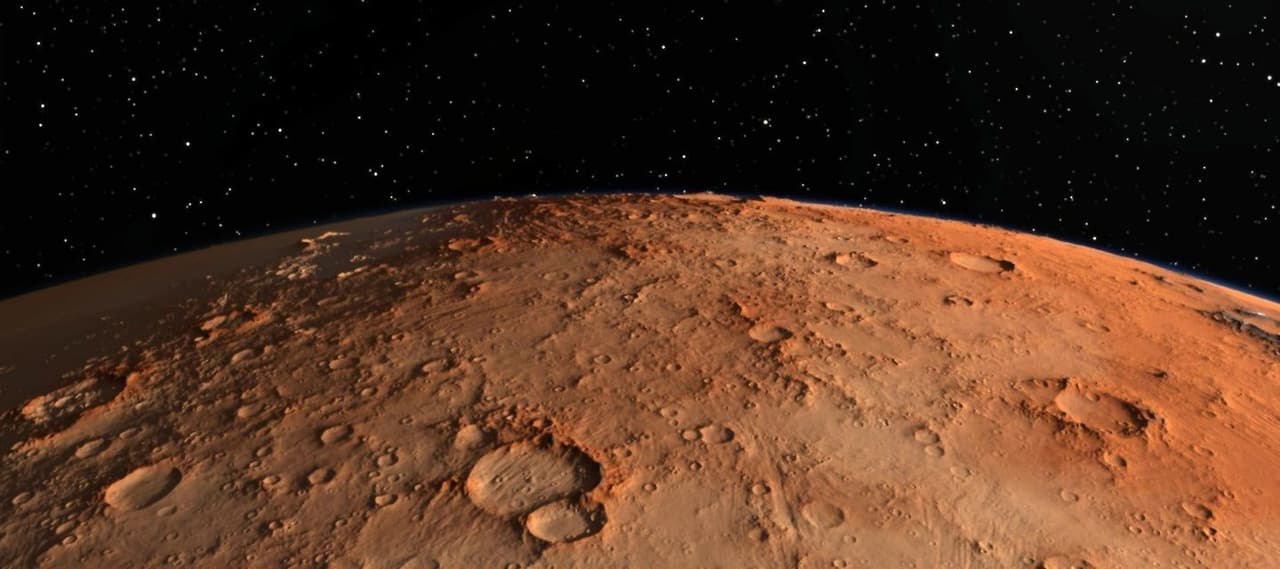 Una vista dall'orbita sulla superficie rossa e craterizzata di Marte, con la curva del pianeta contro uno sfondo spaziale stellato.