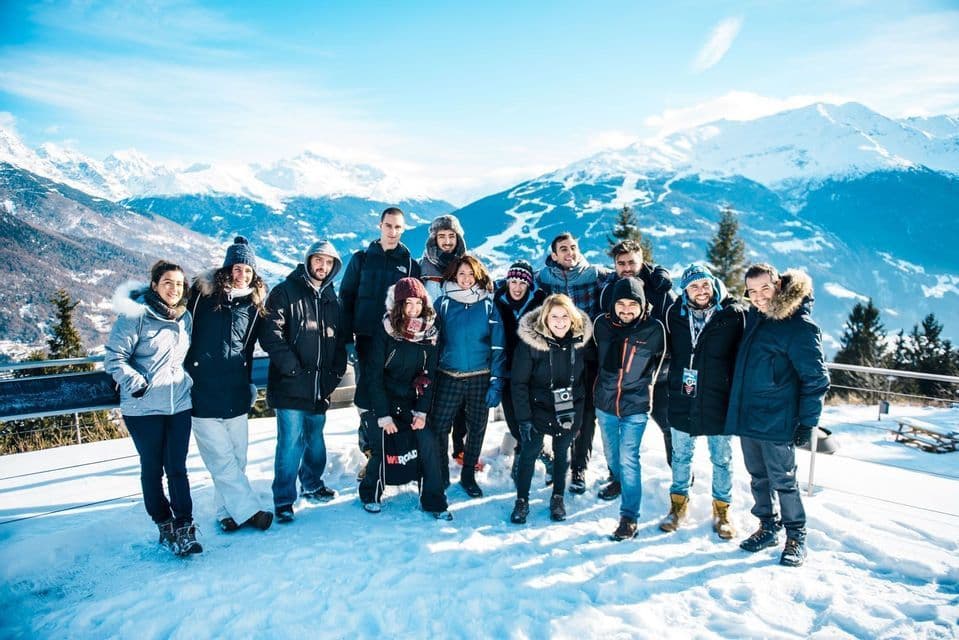 Un grupo de WeRoad posando en una montaña nevada con vista panorámica a otros picos.
