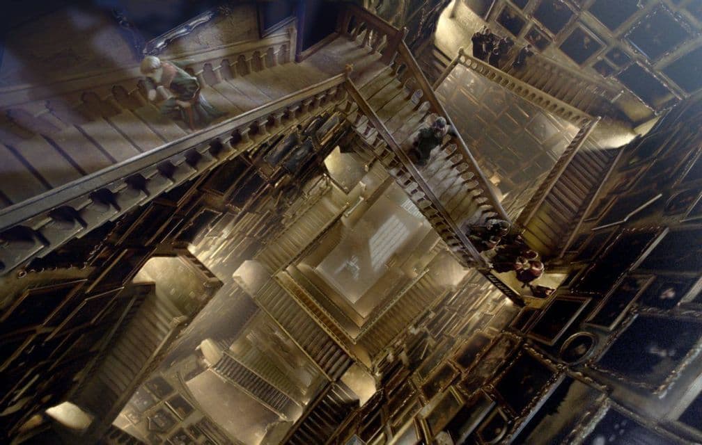 Una prospettiva dall'alto di una complessa scala mobile multilivello all'interno di una vasta sala adornata di ritratti.
