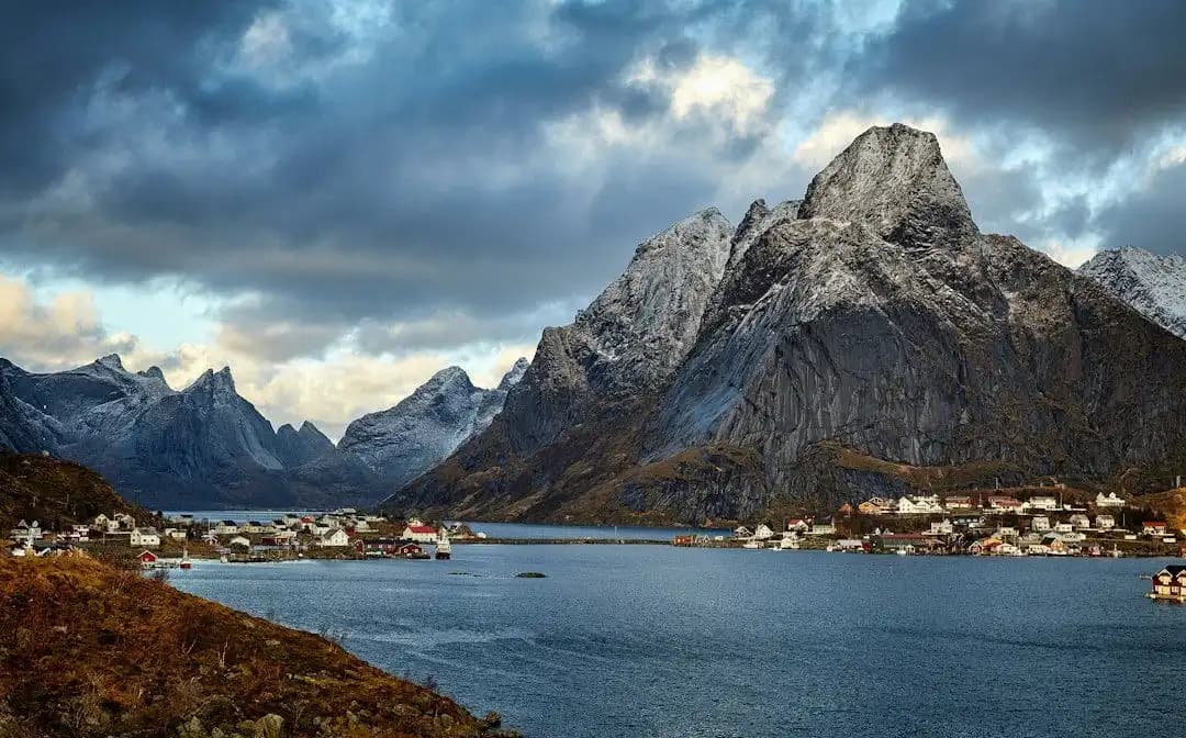 Pueblo de pescadores junto al fiordo y al pie de montañas escarpadas, islas Lofoten, Noruega