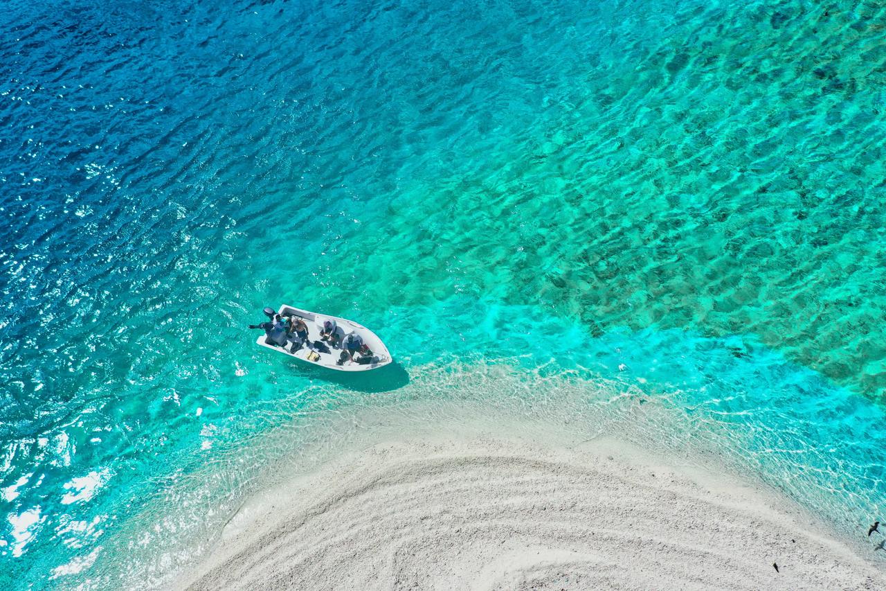 Aerial view of a speedboat next to a white sandbar in turquoise water.