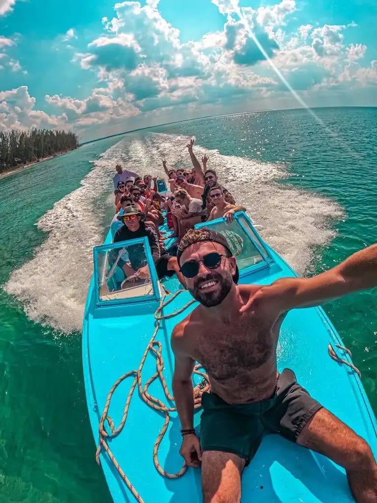 Eine WeRoad-Gruppenreise in einem blauen Boot auf türkisem Wasser, eine Person macht vorne ein Selfie.