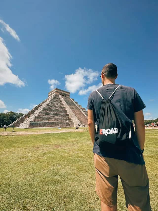 A man with a WeRoad rucksack watching at Chichen Itza - Mexico