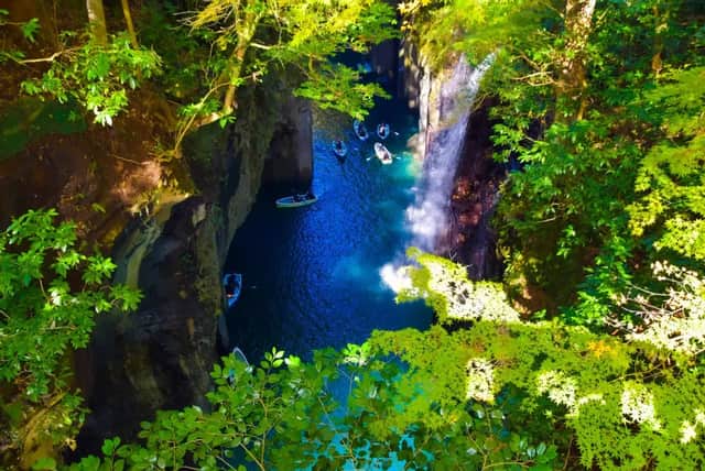 Veduta aerea di un viaggio di gruppo WeRoad che pagaia in barca in una gola stretta con acqua blu vibrante e una cascata.