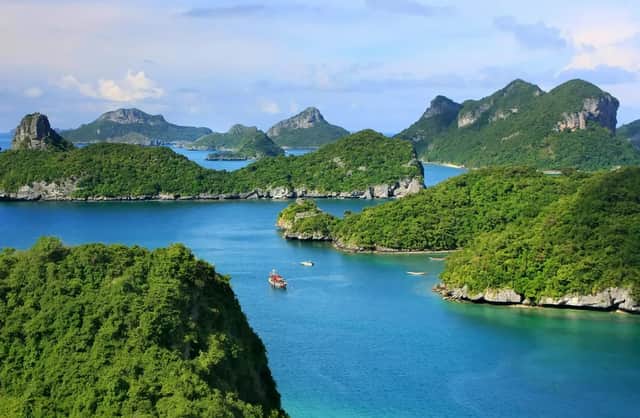 Una vista aerea di un arcipelago con isole verdi e lussureggianti, acqua blu calma e diverse piccole barche che navigano.