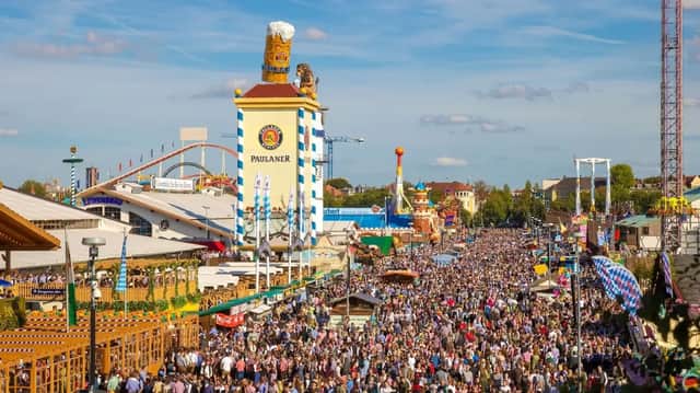 Una veduta aerea di una folla immensa che riempie le strade di un festival all'aperto con grandi tende e giostre.