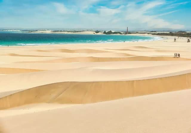 Un viaggio di gruppo WeRoad tra ampie dune di sabbia, affacciate su un oceano turchese sotto un cielo parzialmente nuvoloso.