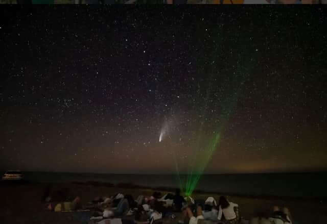 Un viaggio di gruppo WeRoad per osservare le stelle e una cometa su una spiaggia di notte, sotto un cielo stellato.