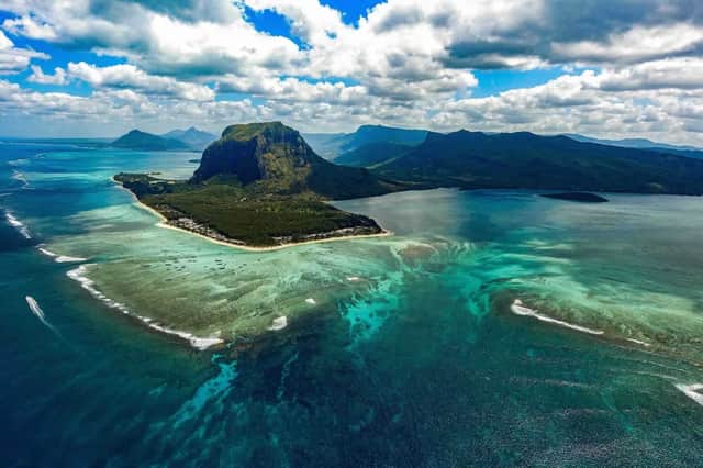 Una vista aerea di una montagna su una penisola con un'illusione ottica di una cascata sottomarina nell'oceano turchese.