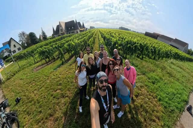 Un viaggio di gruppo WeRoad in posa per un selfie grandangolare accanto a filari di viti verdi sotto un cielo azzurro.