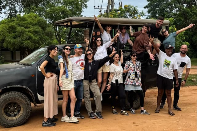 Un grupo de WeRoad posa sonriente junto a un todoterreno de safari.